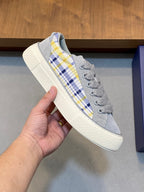 Grey low-top sneaker with blue-yellow plaid side stripe and lace closure