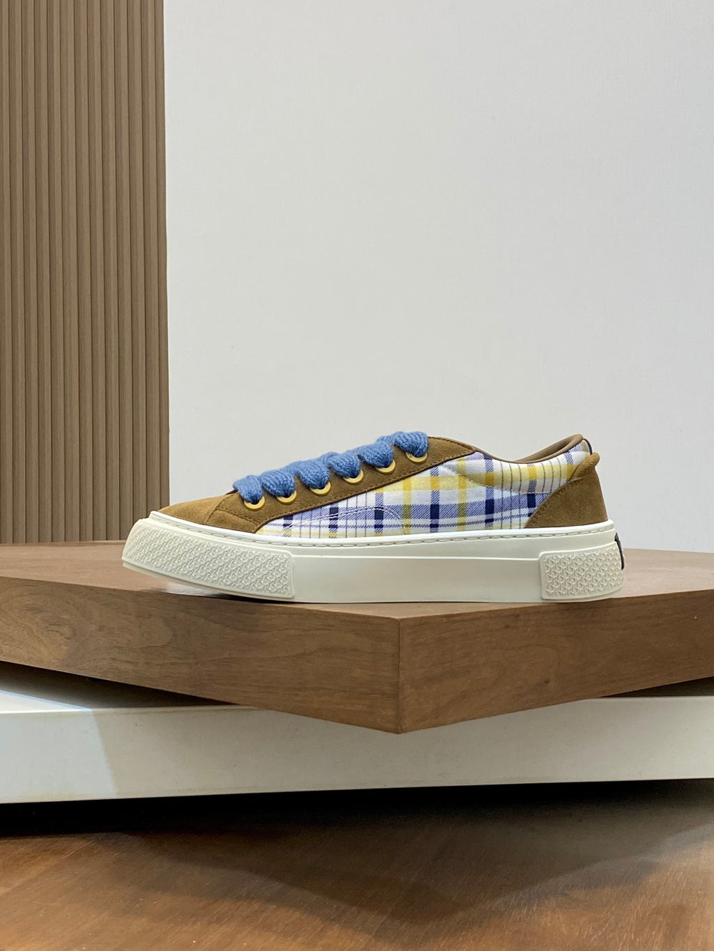 Low-top sneakers with blue laces and plaid upper, white sidewall and textured sole.