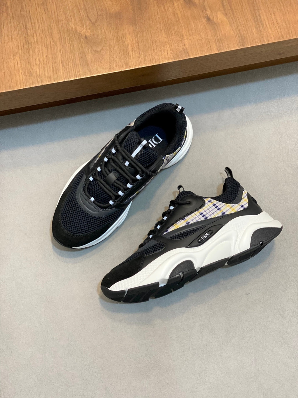 Pair of navy Dior sneakers with plaid side panels, lace-up design and chunky white soles