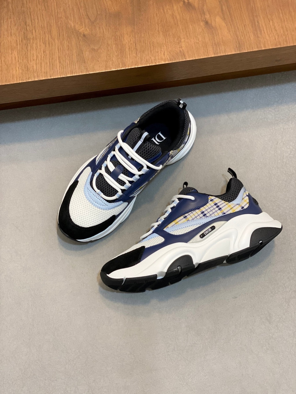 Dior unisex sneakers on floor; navy, white, and light blue colorblock with lace-up