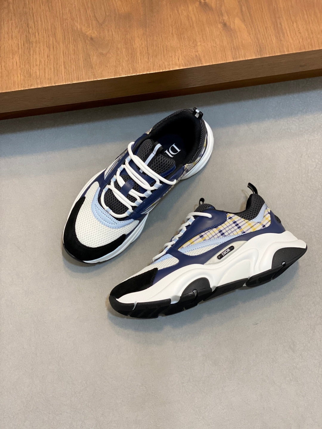 Dior unisex sneakers on floor; navy, white, and light blue colorblock with lace-up