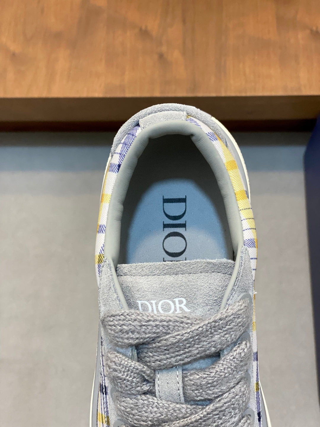Grey low-top sneaker tongue with Dior logo and blue-yellow check lining