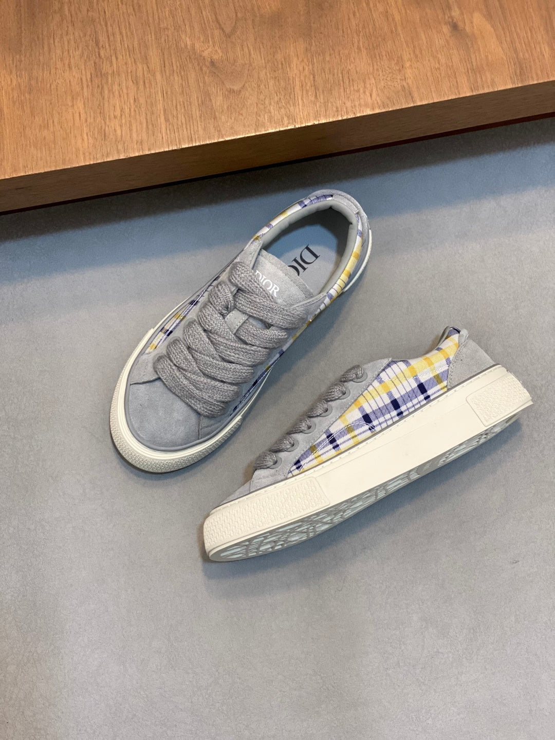 Grey low-top Dior sneakers with blue-yellow plaid detail on side