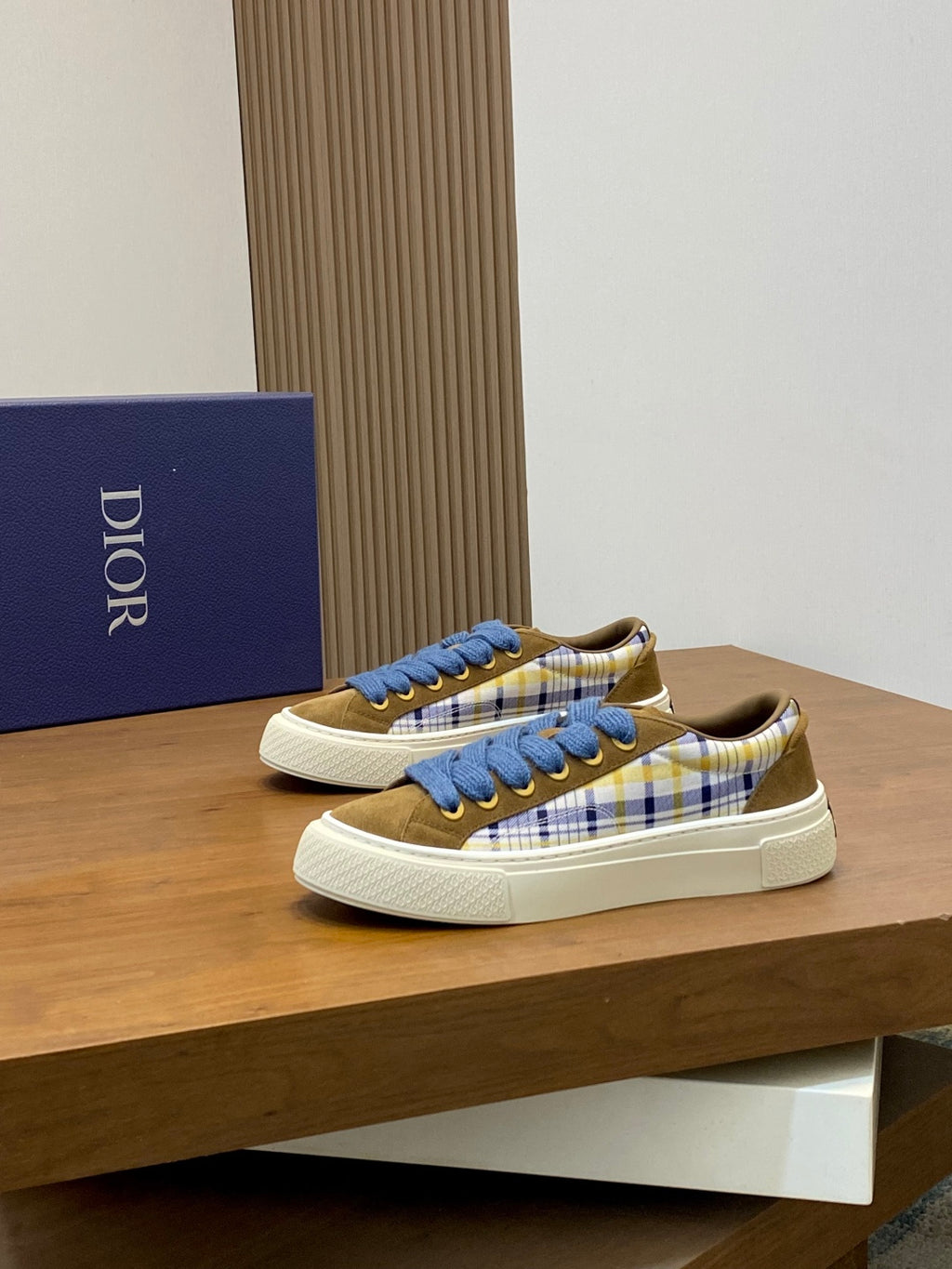 Pair of low-top plaid sneakers with blue laces and white rubber sole, brown suede heel.