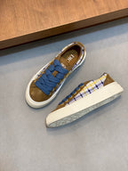 Low-top sneakers in plaid with blue laces and white sole, brown suede interior lining.