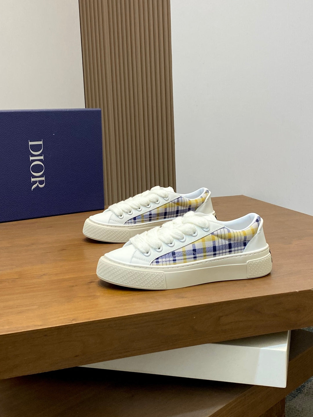 White lace-up sneakers with blue plaid accents and textured rubber outsole.