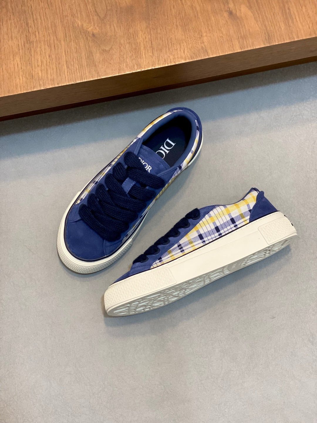 Pair of navy blue low-top sneakers with yellow-and-white plaid side stripe and white sole.