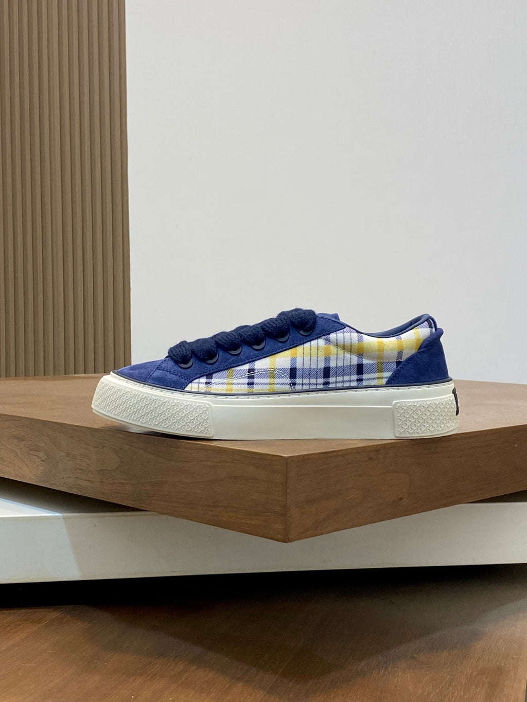 Navy blue low-top sneakers on display with plaid side stripe and white rubber sole.