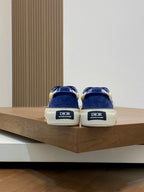 Back view of navy blue sneakers with 'Dior' logo on heel and white rubber soles.
