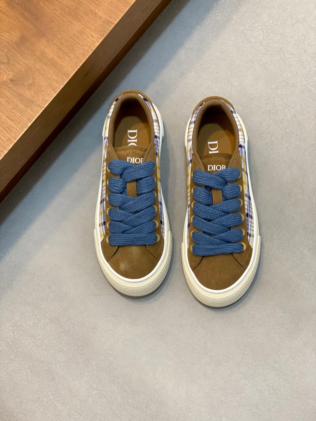 Low-top sneakers with blue laces and plaid fabric panels, tan interior, white rubber sole.