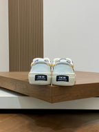 Back view of white low-top sneakers with Dior heel tabs and blue plaid lining.