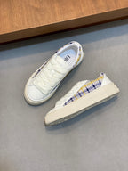 Pair of white low-top sneakers with blue plaid trim, lace-up.