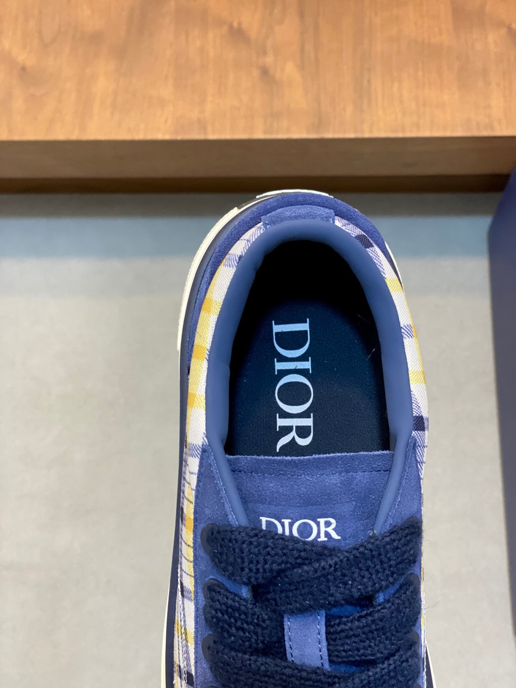 Navy blue sneaker interior view with 'Dior' logo on tongue and lace-up front.