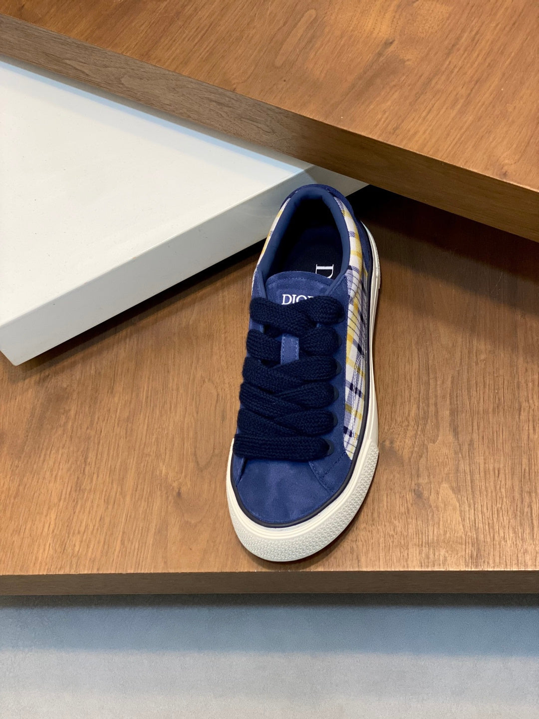 Navy blue low-top sneakers with lace-up front and plaid trim along the side.