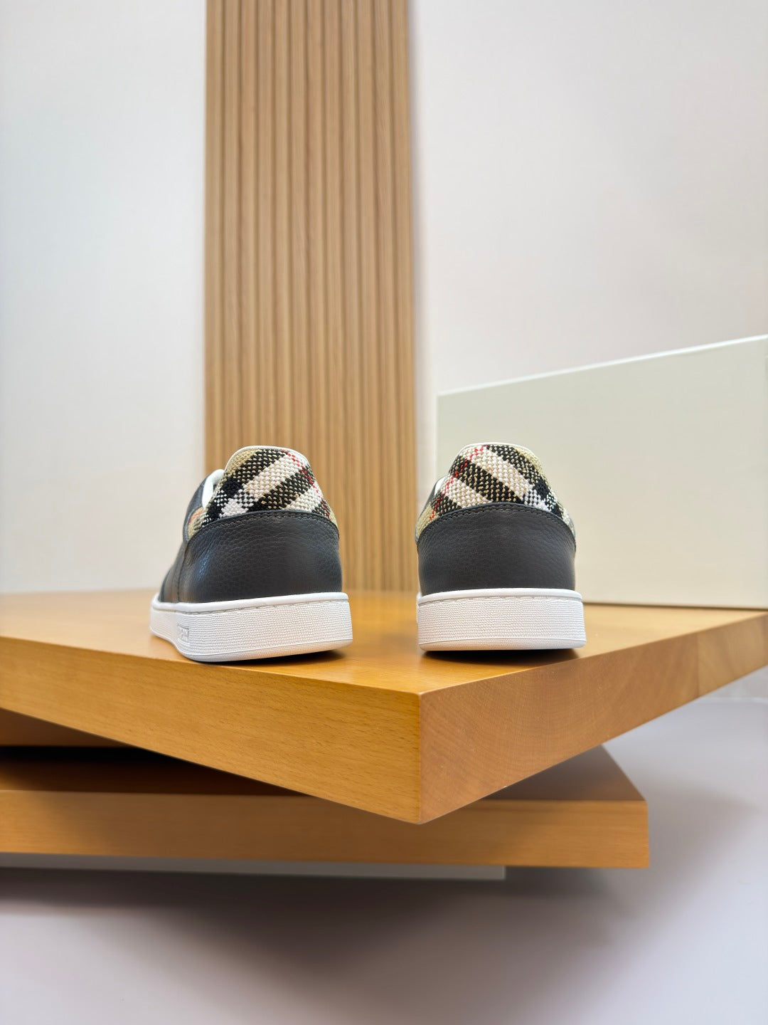 Back view of dark leather sneakers with white soles and check-pattern heel accents