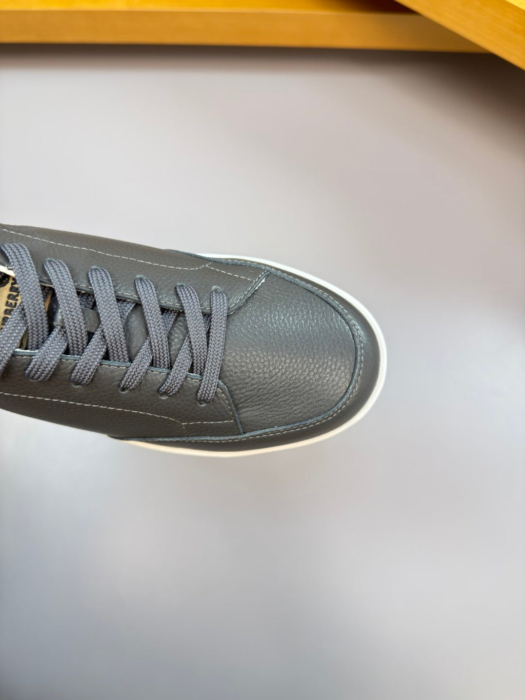 Close-up of dark leather sneaker upper with gray laces and white edge sole