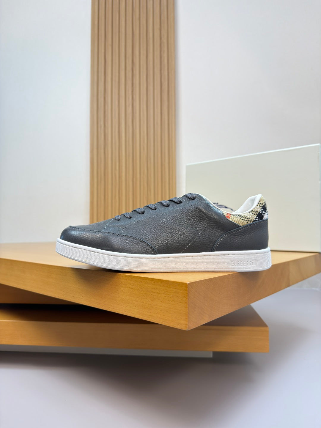 Dark navy leather low-top sneakers with white sole, side view on display