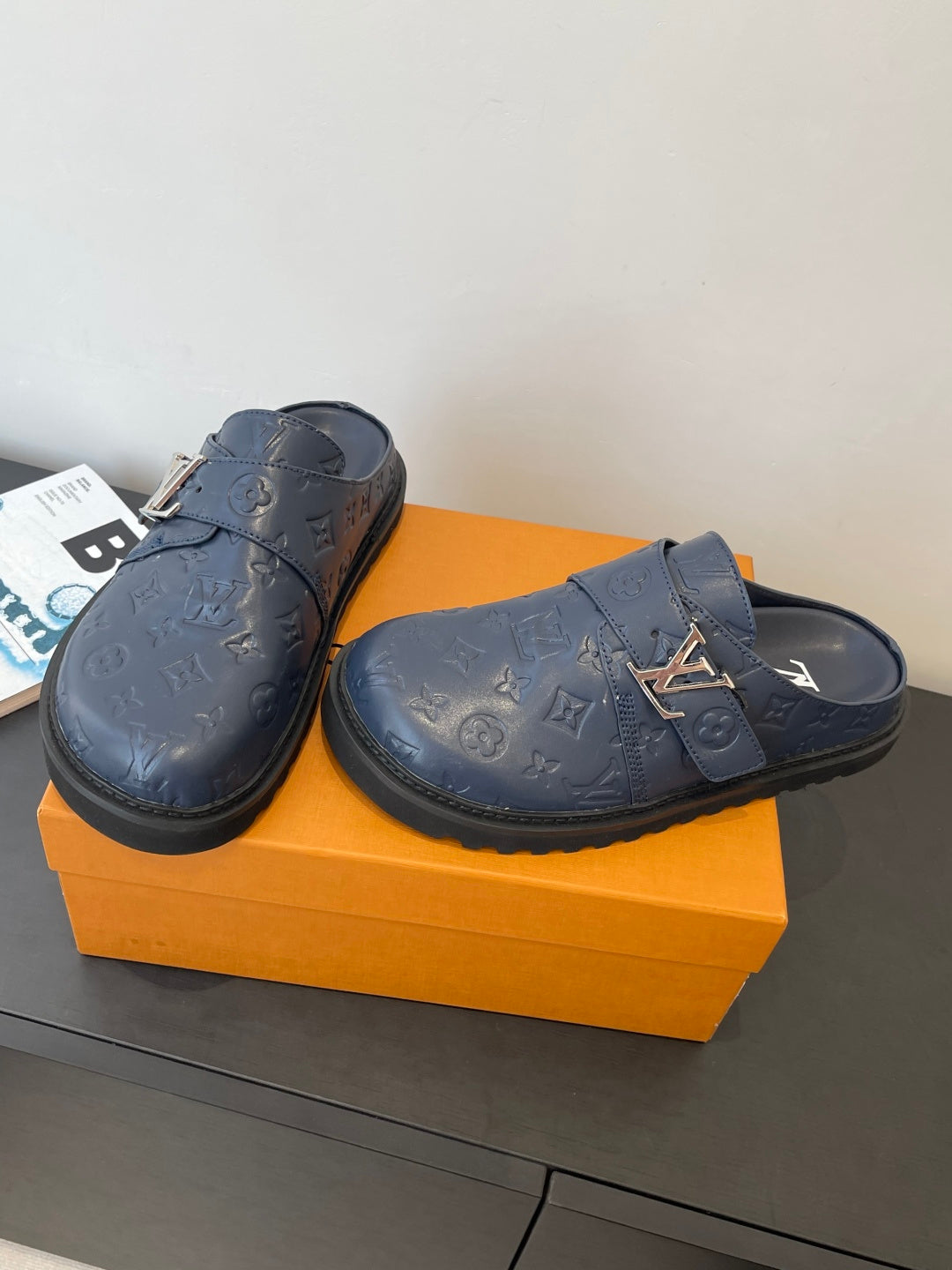 Louis Vuitton navy embossed slide sandals with gold logo accents on straps