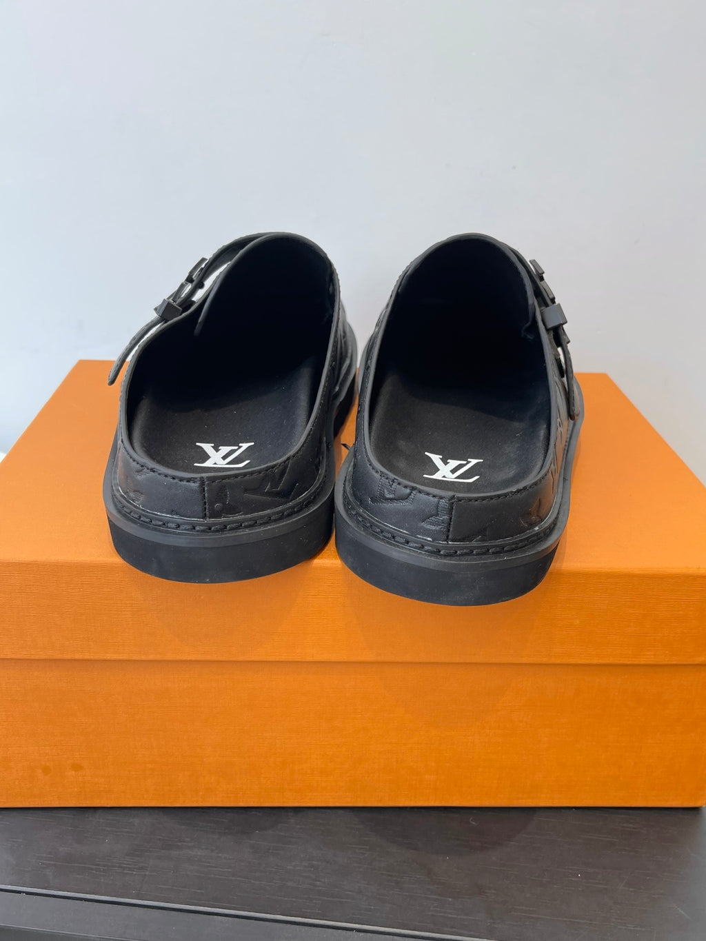 Louis Vuitton slide sandals with dark leather straps and embossed LV logo