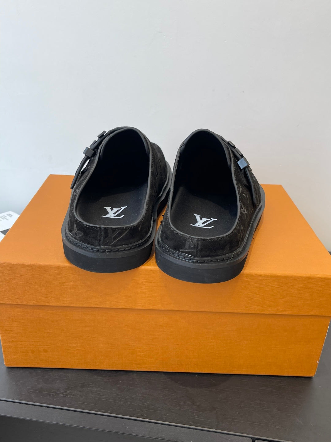 Louis Vuitton black monogram slide sandals, rear view with embossed LV on footbeds
