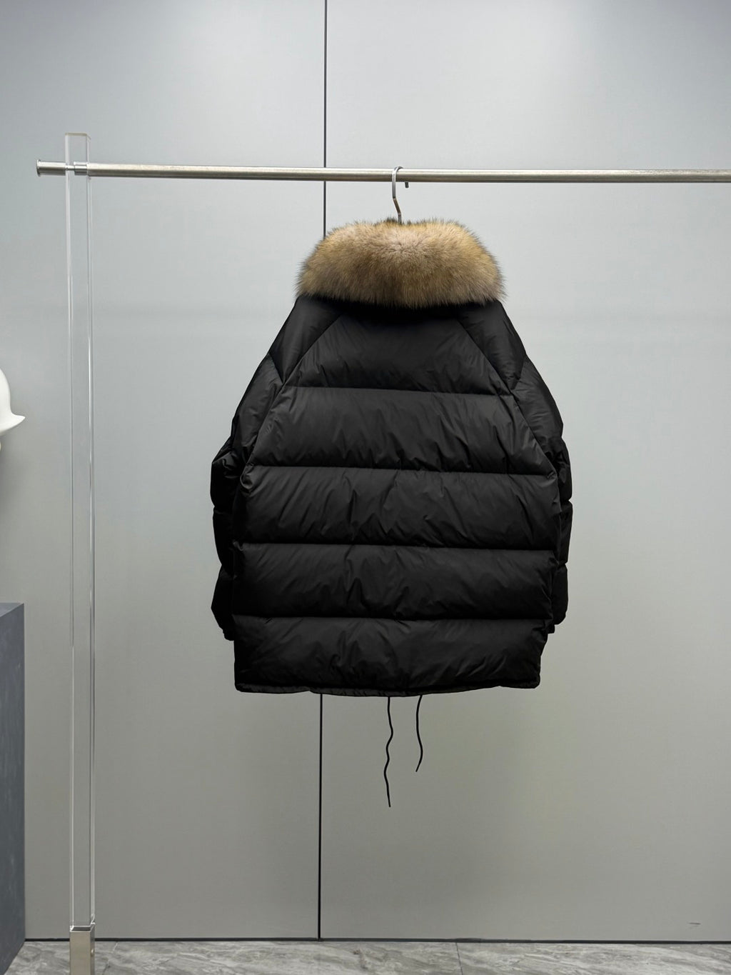 Long black puffer jacket back view on hanger with tan fur hood trim