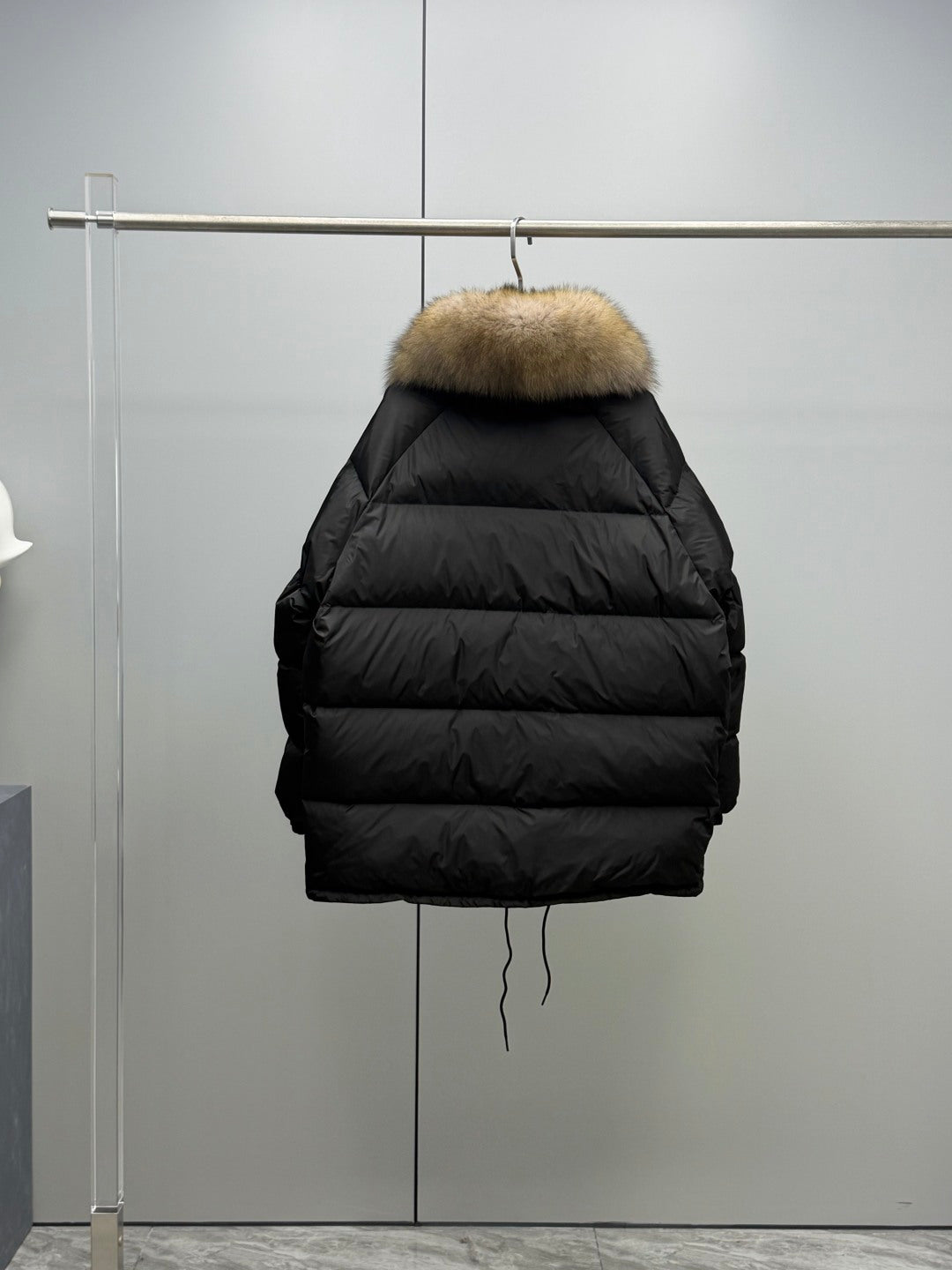 Long black puffer jacket back view on hanger with tan fur hood trim
