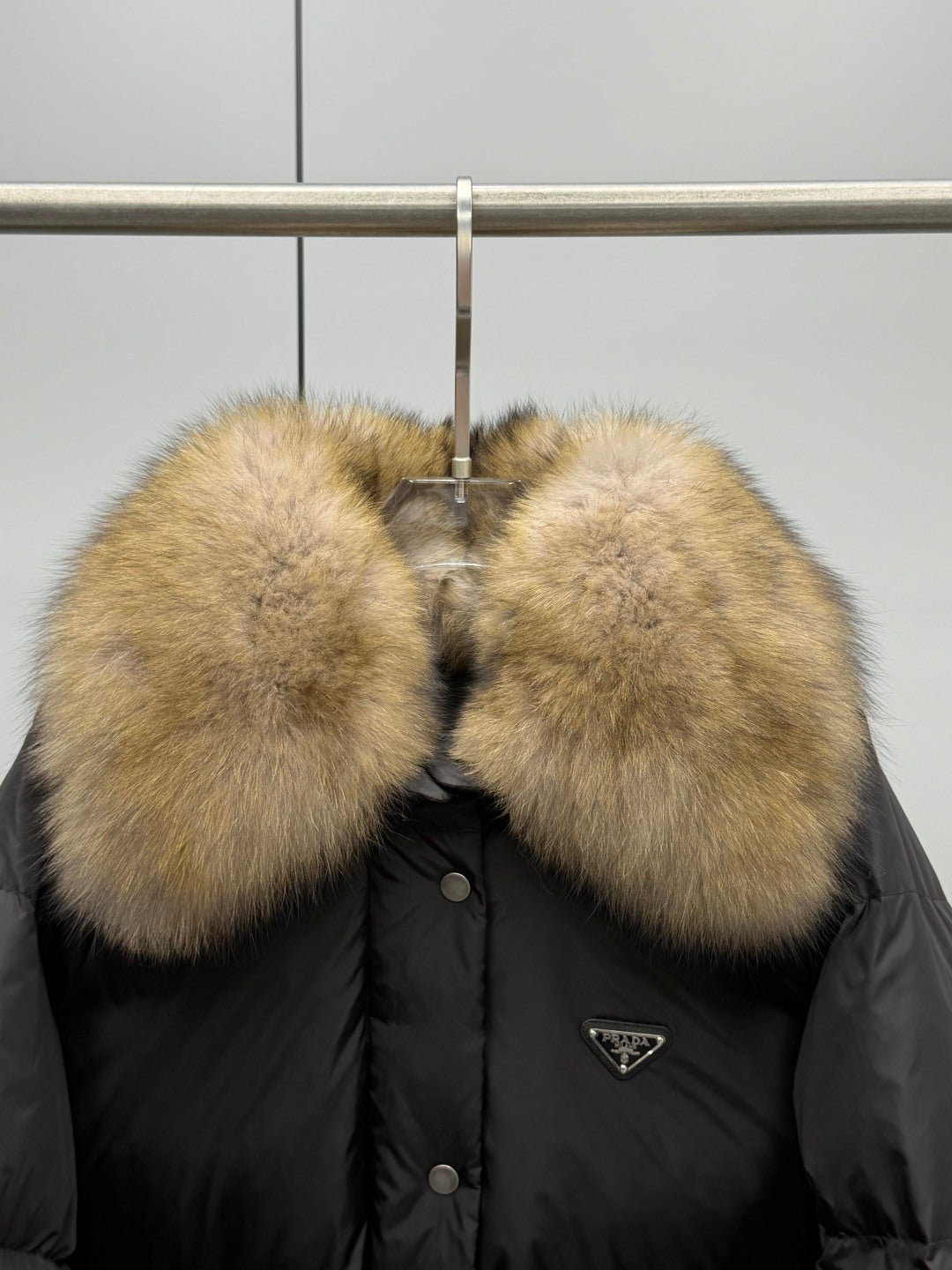 Black puffer jacket with oversized tan fur collar and snap buttons