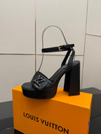 Women’s black platform heeled sandals on orange box, with slingback strap and V buckle.