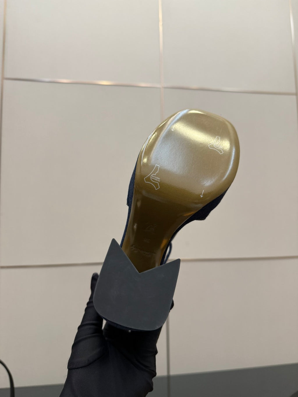 Black platform heel sole viewed from side, with inner gold logo stamp