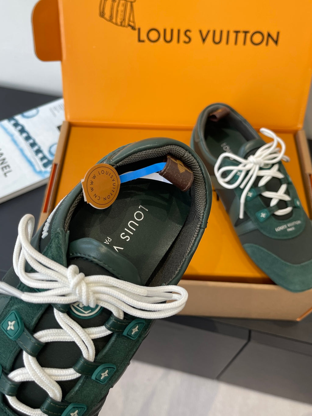 Teal lace-up sneaker with white laces and tan emblem patch at heel
