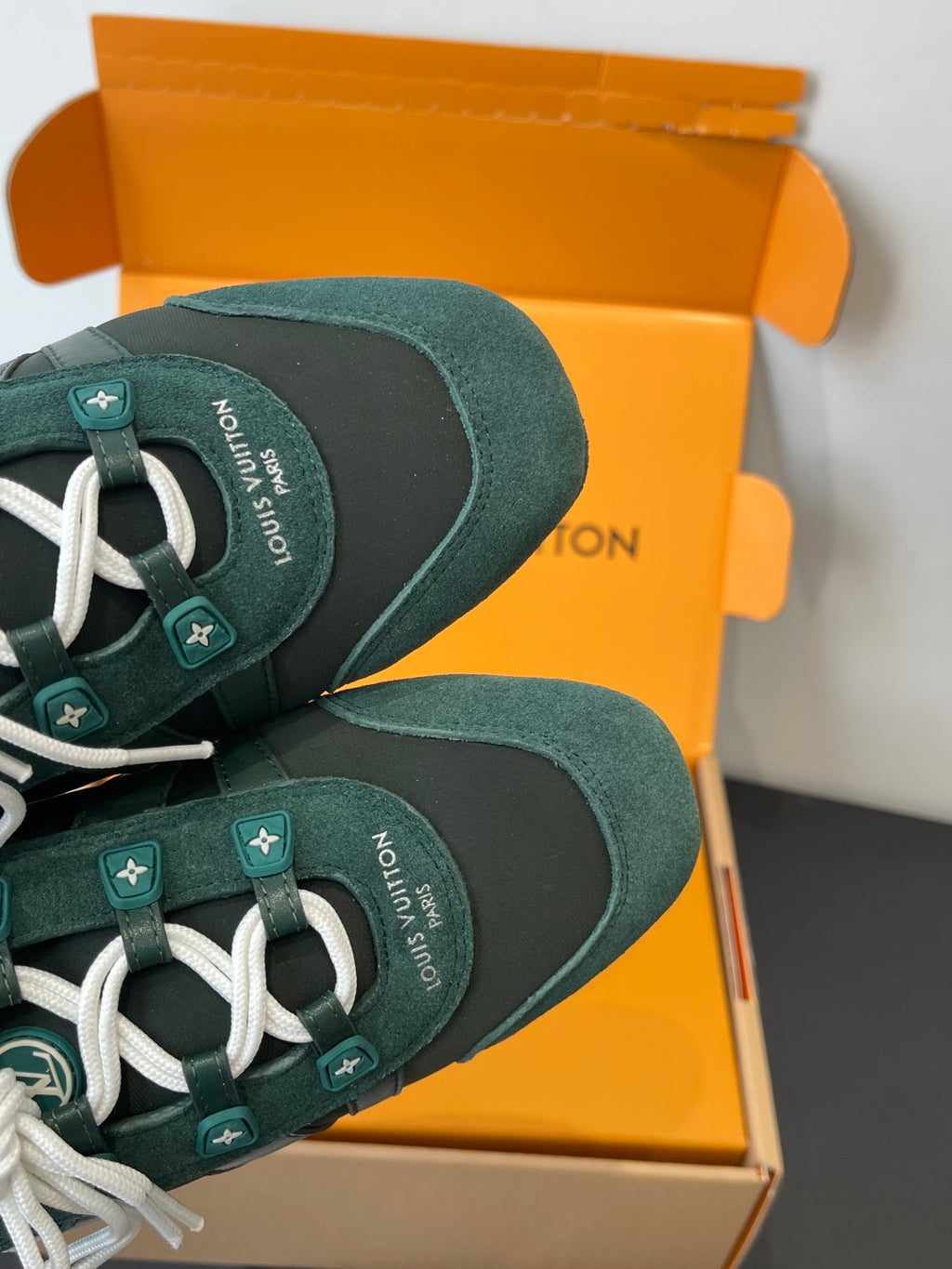 Teal lace-up sneakers close-up on toe and white laces with small logo tags