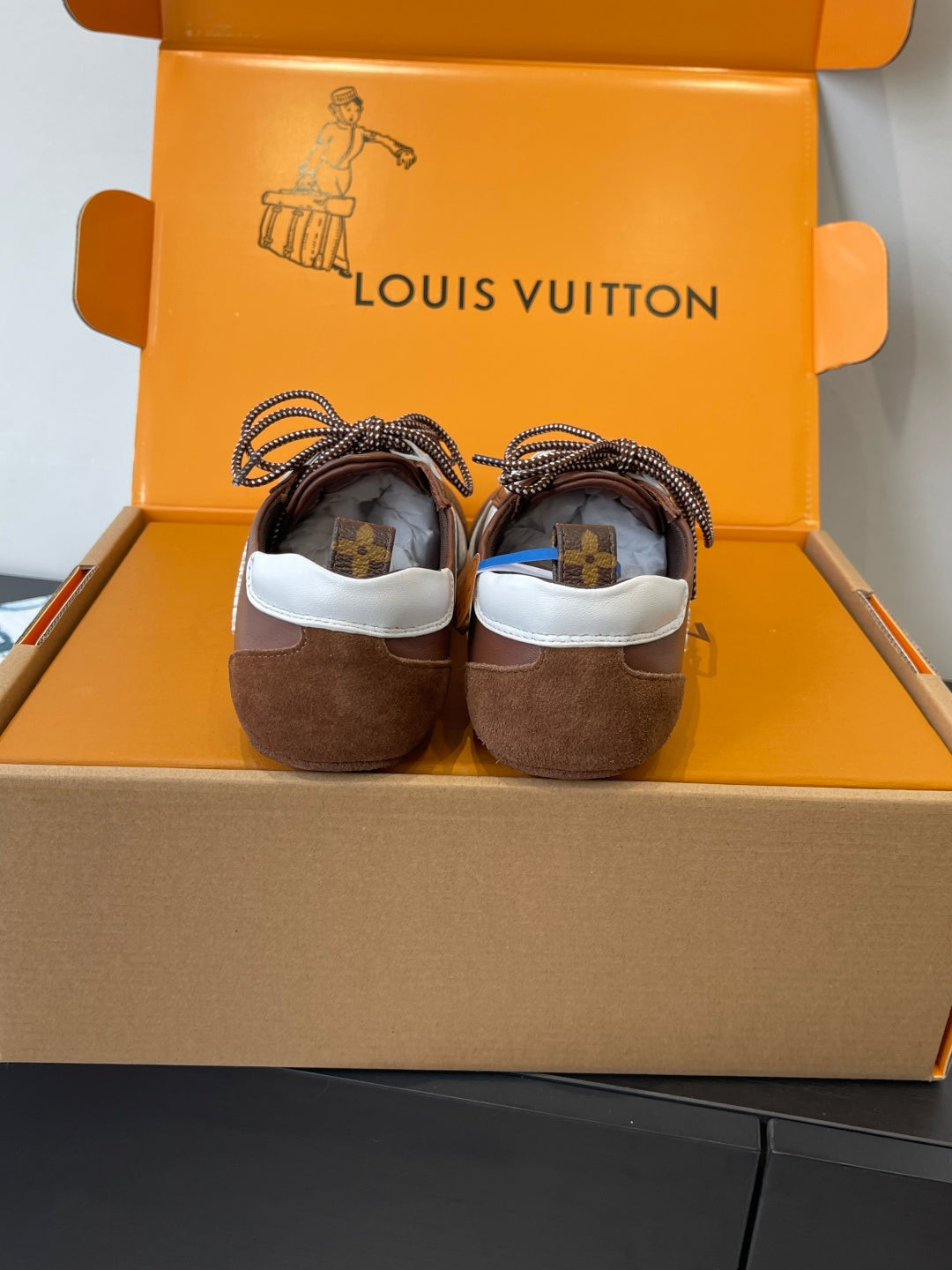 Unisex Louis Vuitton sneakers, rear view showing brown suede heels and white trim
