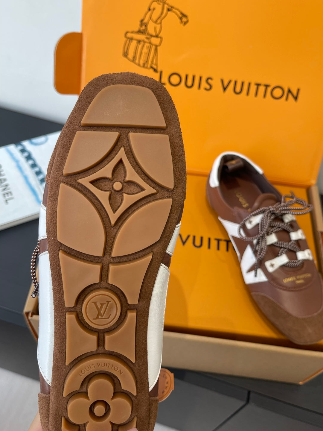 Brown sneaker outsole with patterned emblem, plus side view shoe