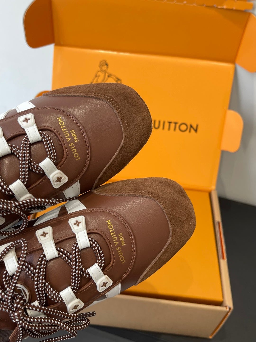 Brown lace-up sneaker heel with white logo patch and beaded cord laces