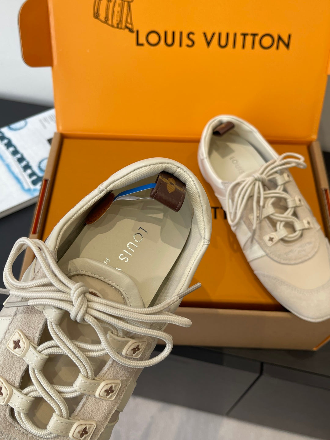 Louis Vuitton sneakers close-up, cream canvas upper with star-stud eyelets, in box