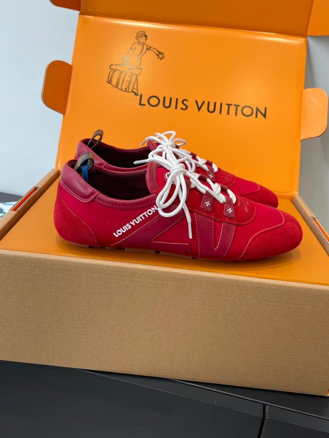 Louis Vuitton unisex red sneakers with white laces, side view in open shoebox