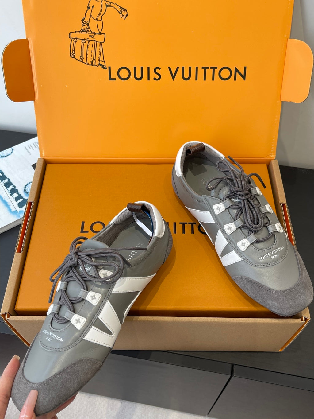 Pair of gray and white Louis Vuitton lace-up sneakers in box, side and front views