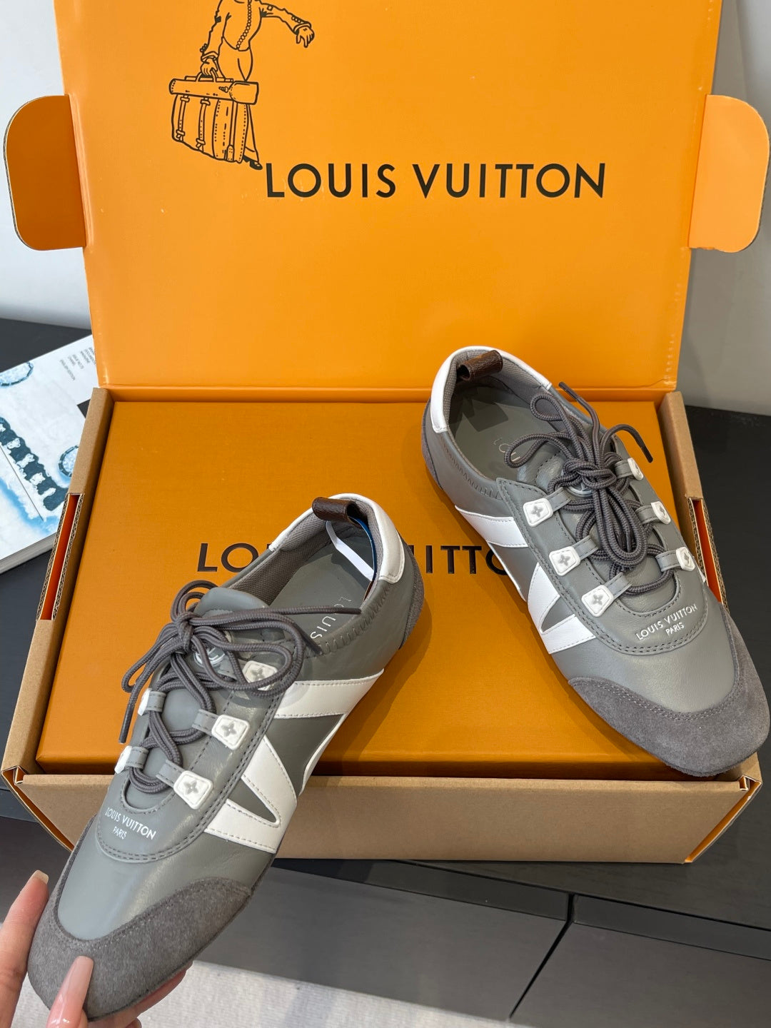 Pair of gray and white Louis Vuitton lace-up sneakers in box, side and front views
