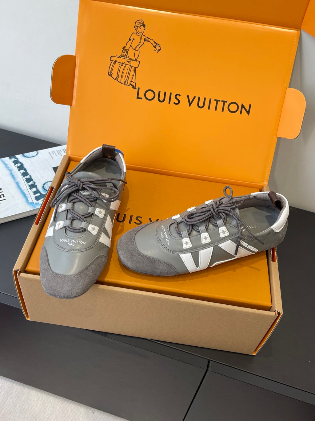 Gray and white Louis Vuitton lace-up sneakers, one shoe turned to show side stripe