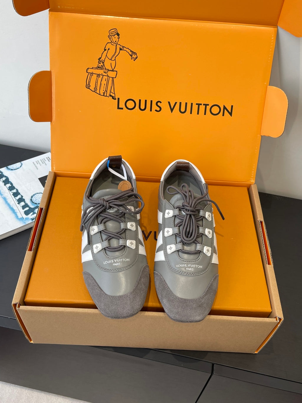 Gray and white lace-up Louis Vuitton sneakers, front view with signature side stripe