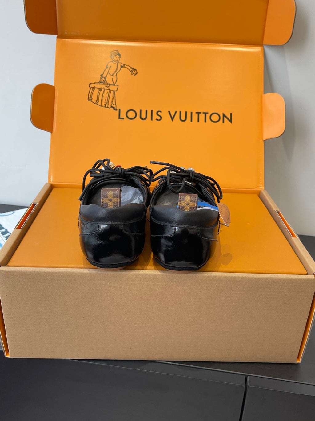 Louis Vuitton unisex black sneakers resting in open box, front view
