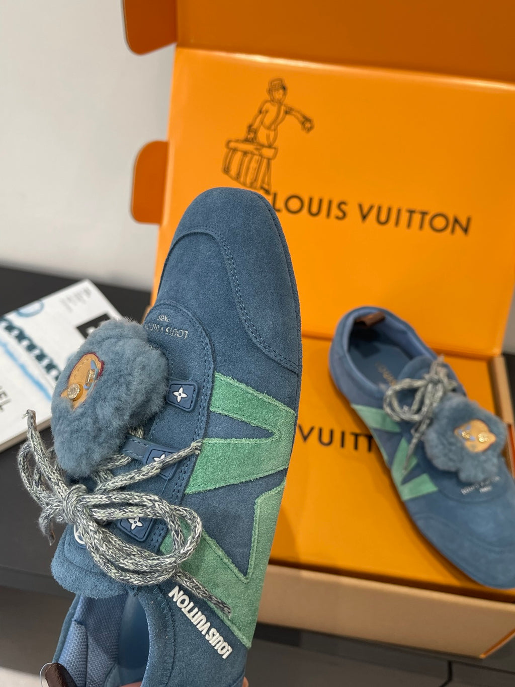 Unisex blue suede sneaker with fuzzy tongue and bear-face patch, green stripe