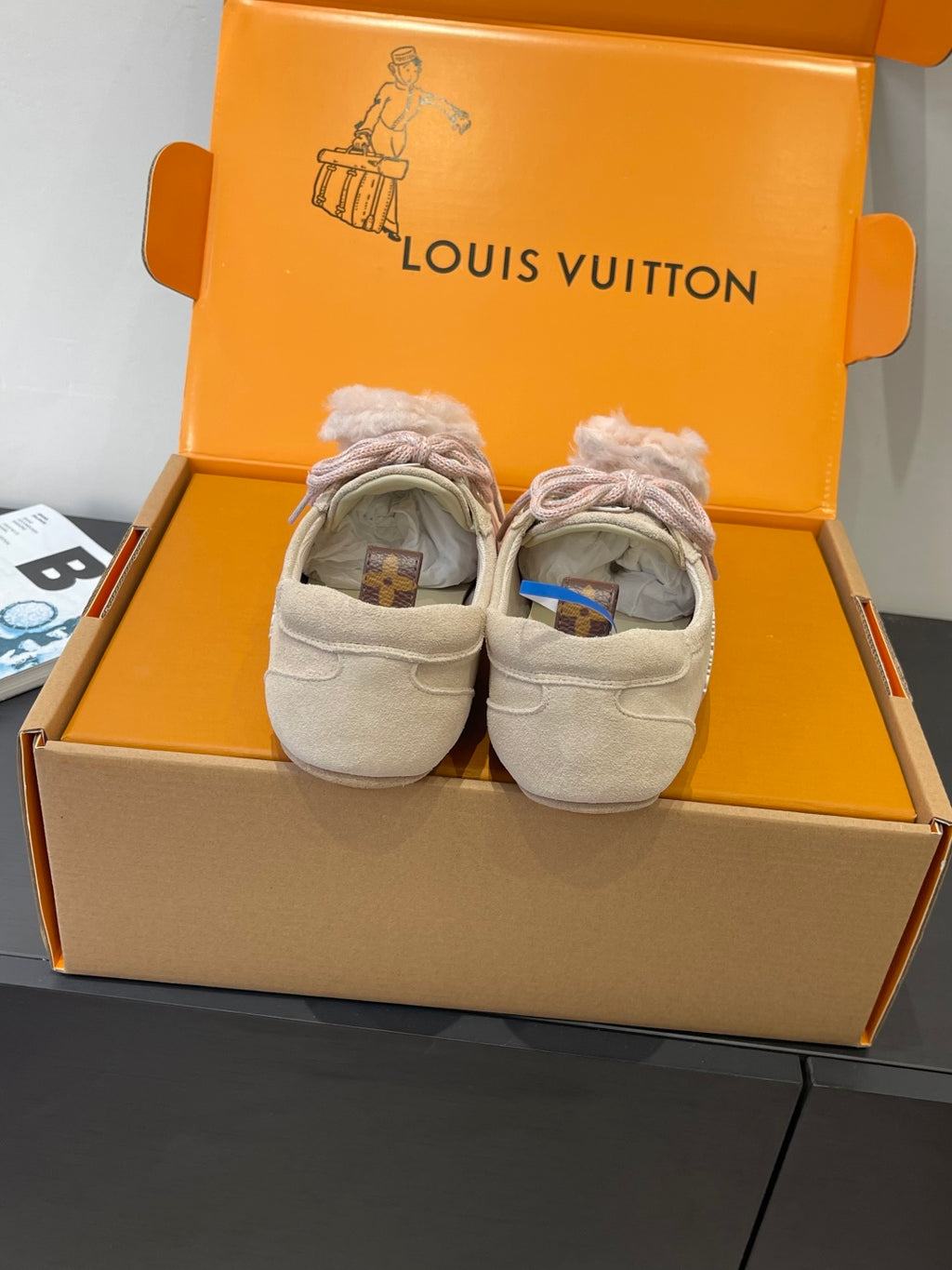 Pair of beige suede sneakers with pink laces and fur-trimmed cuffs in box