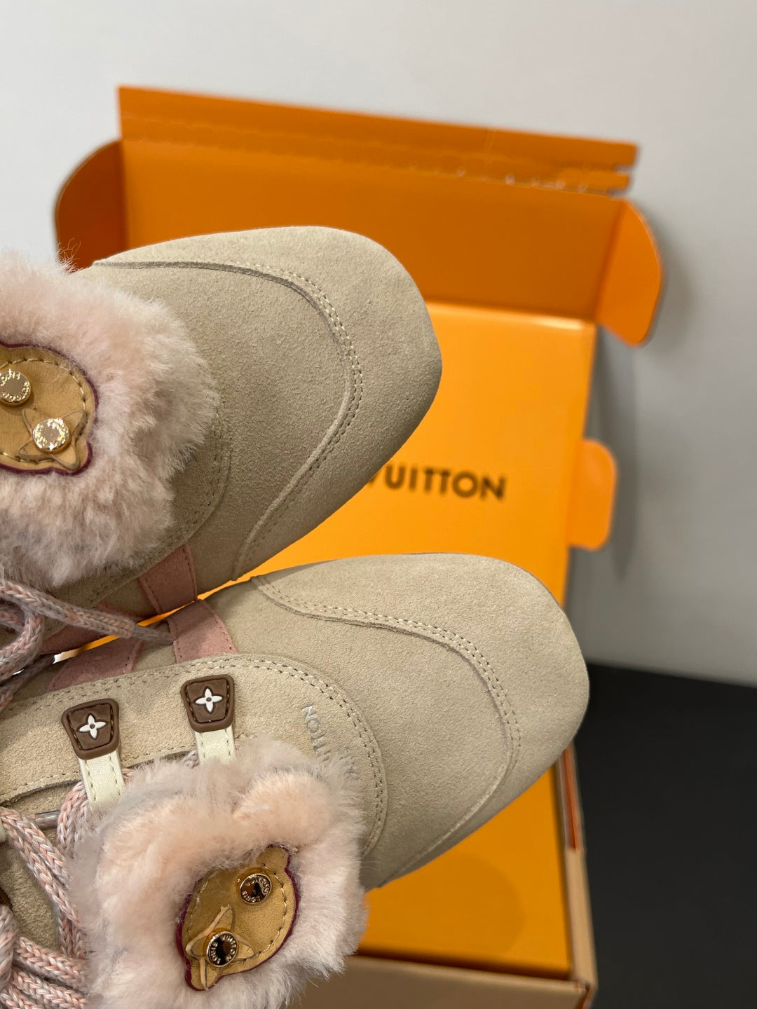 Beige suede sneaker toe and fur cuff with pink lace detail, close-up