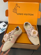Pair of beige suede sneakers with pink laces and fur trim, angled view in box