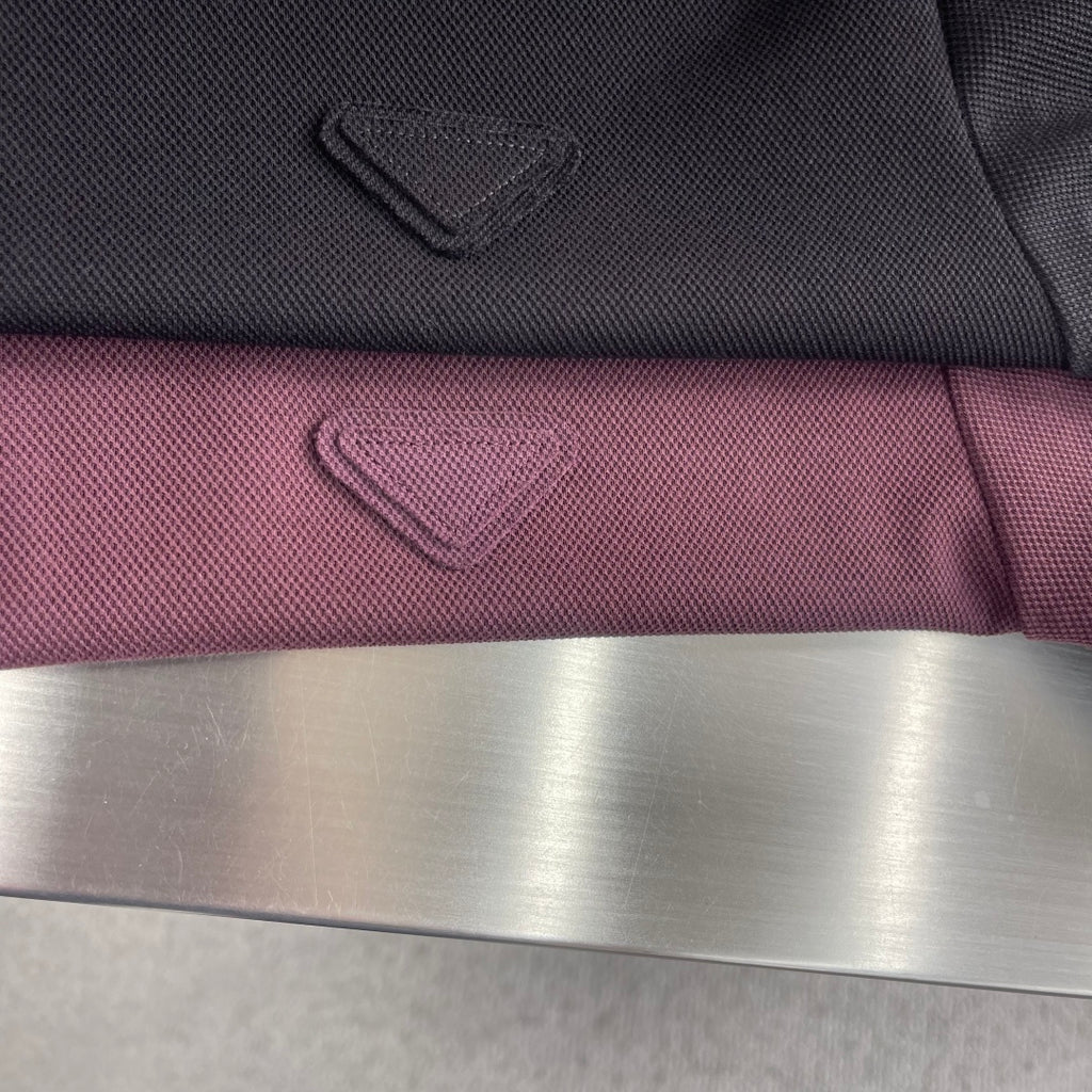 Prada polo shirt logo embroidery on burgundy fabric, close-up with fold