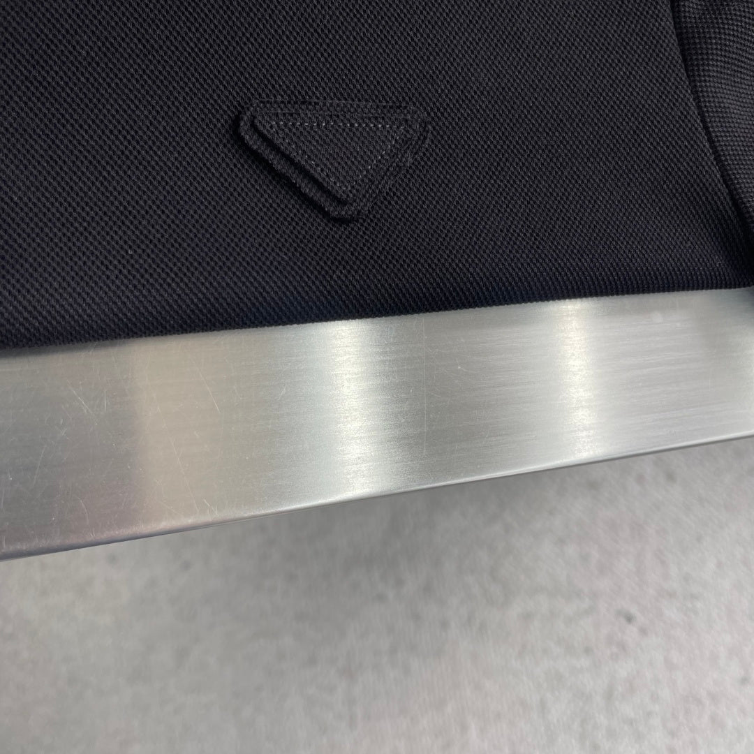 Prada polo shirt chest pocket detail, dark textured fabric with stitched emblem