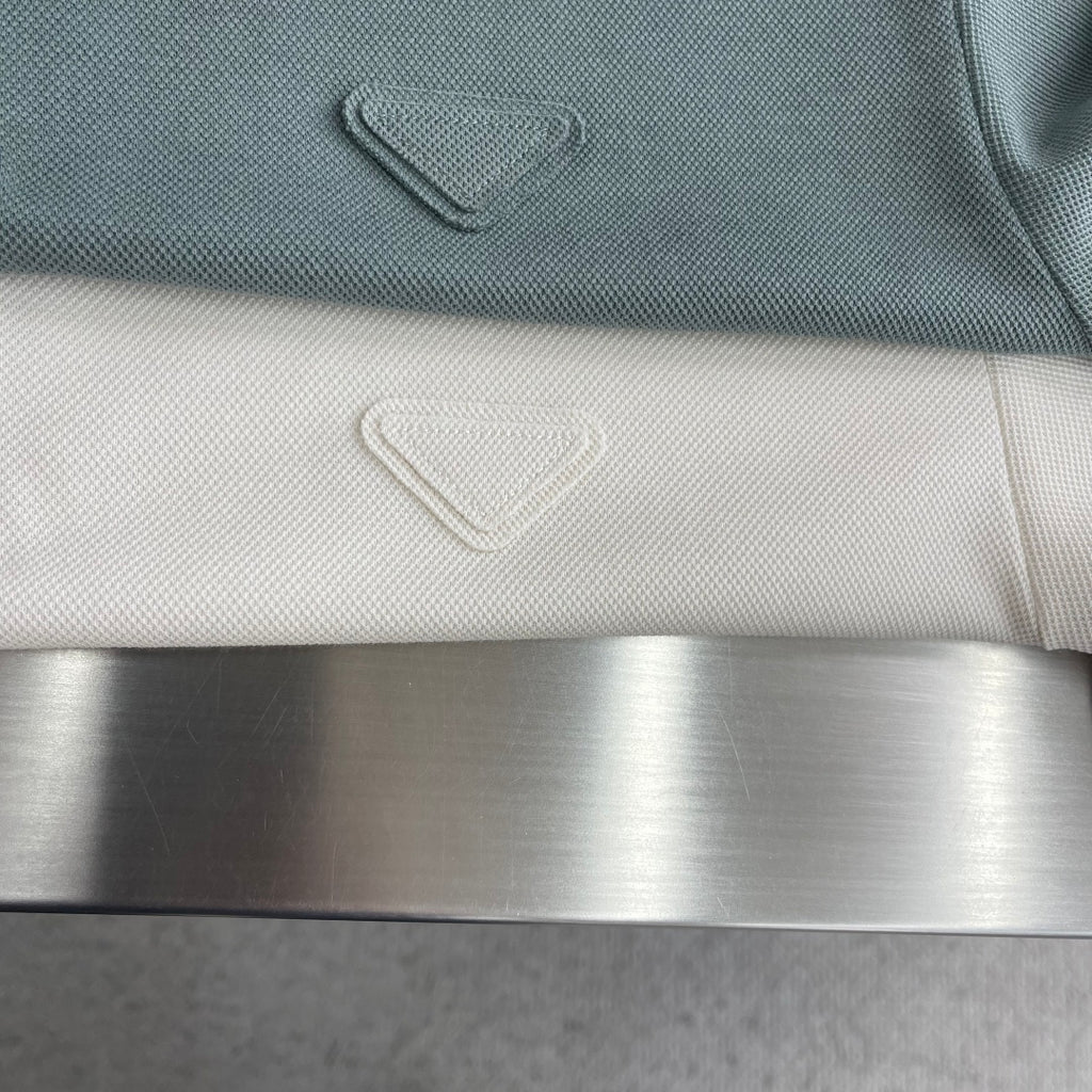 Prada polo shirt close-up of small chest emblem on muted teal knit