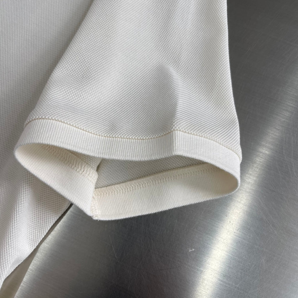 Prada polo shirt hem and sleeve cuff in off-white, folded edge detail.