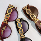 Louis Vuitton sunglasses with gold chain strap detail and purple-brown tinted lenses